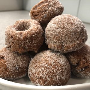 Image of dark, round donut cacao, five-spice donut piled high on a white plate.