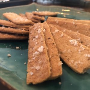 A grouping of 12 rectangular shaped rosemary sea salt batons on a teal colored plate.