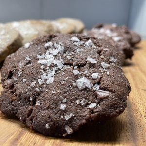 Image of several triple chocolate salted caramel cookies on a wooden board.