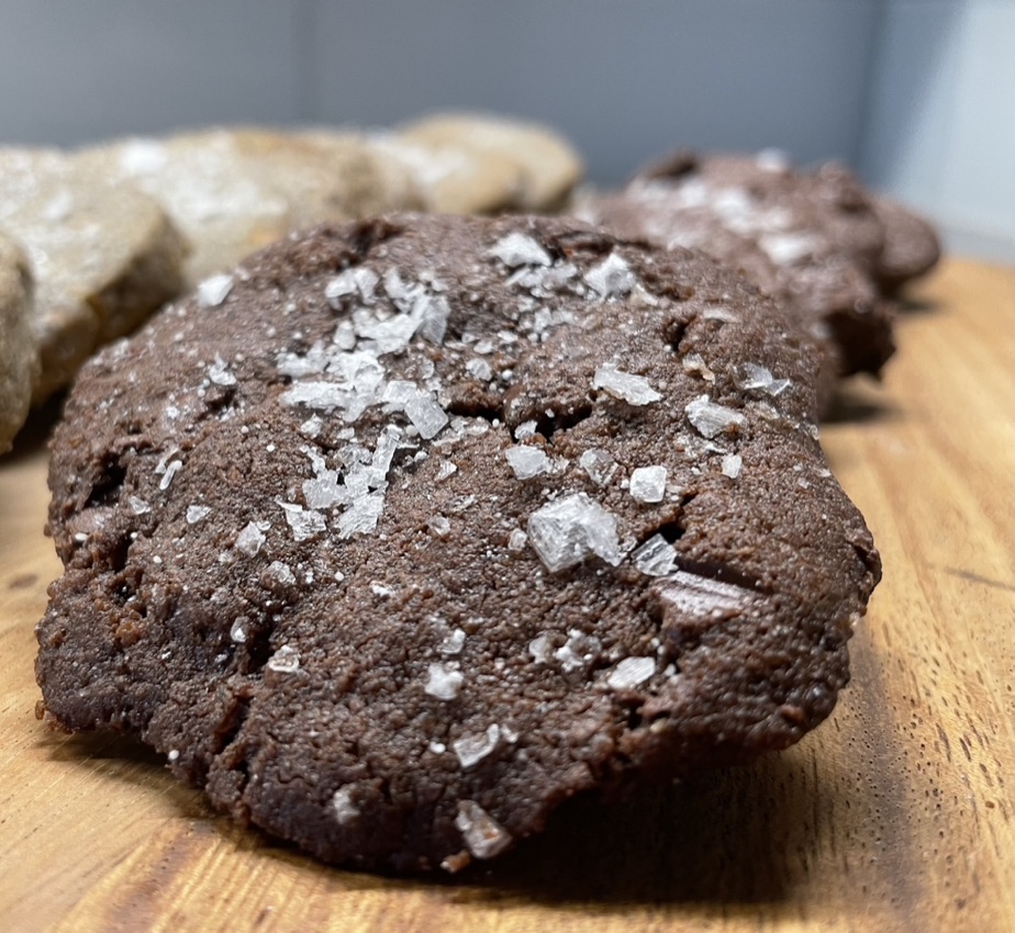 Image of several triple chocolate salted caramel cookies on a wooden board.