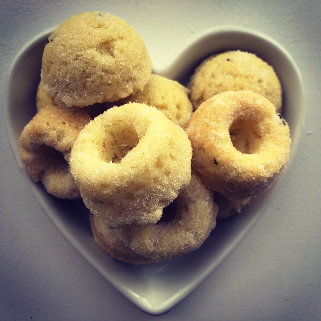 A group of olive oil lemon rosemary donut bites on a white heart-shaped dish.