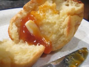 An image of an open popover with jam and butter.